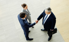 Three businesspeople meet and shake hands
